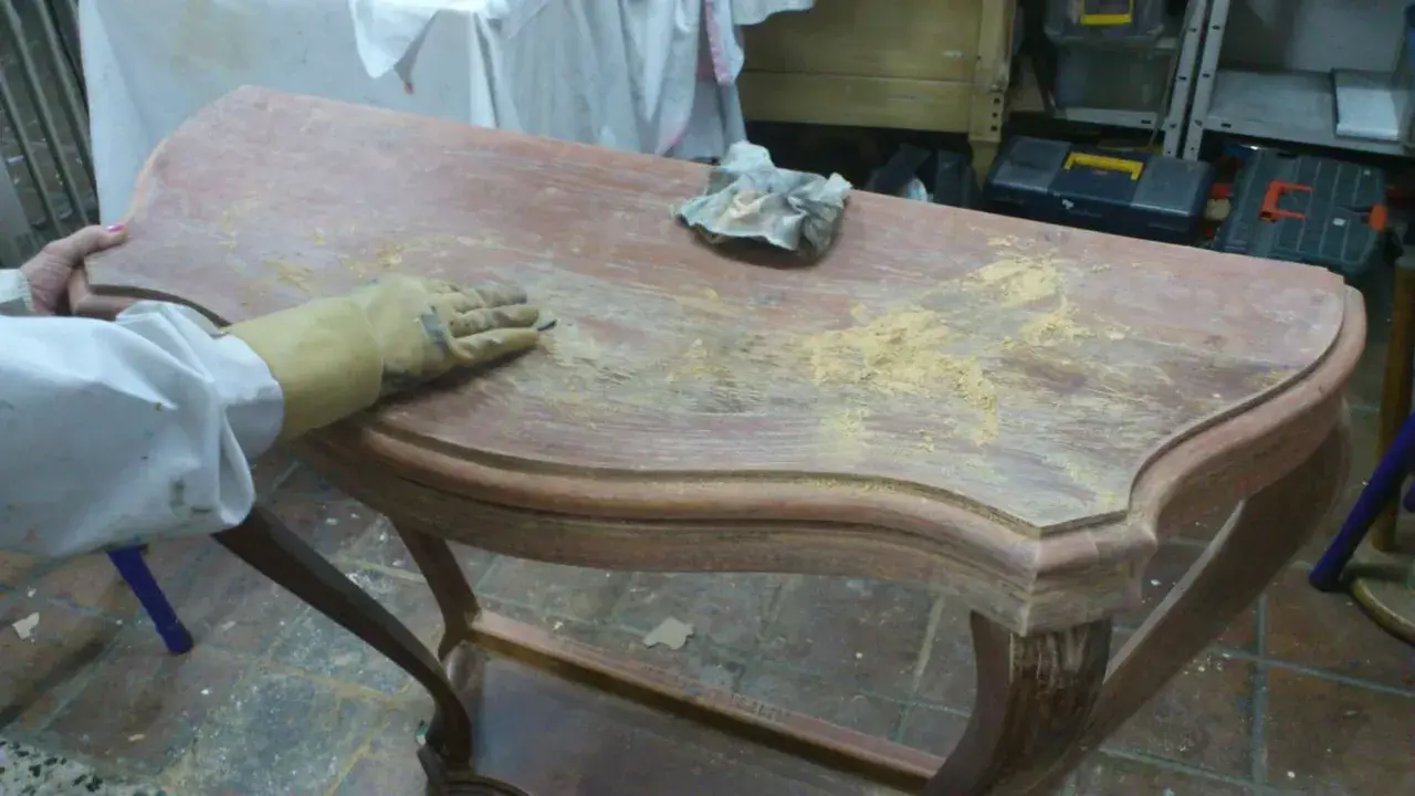 Proceso de como decapar un mueble antiguo, lijando la superficie para eliminar la pintura vieja.