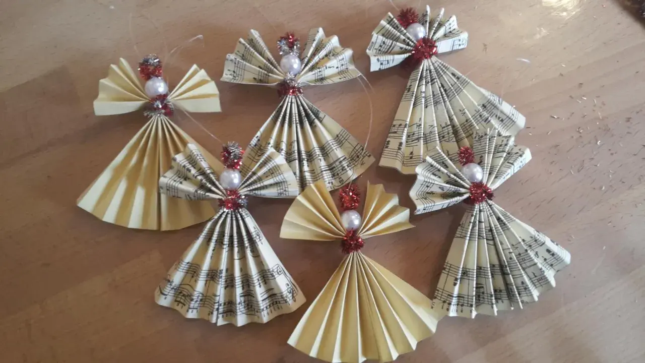 Selbstgemachter Christbaumschmuck: Kleine Weihnachtsengel aus Notenpapier und Perlen, die zum Basteln einladen.