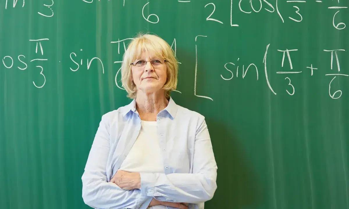 Nauczycielka matematyki przed tablicą z równaniami. Czy doczekamy się wcześniejszych emerytur dla nauczycieli?