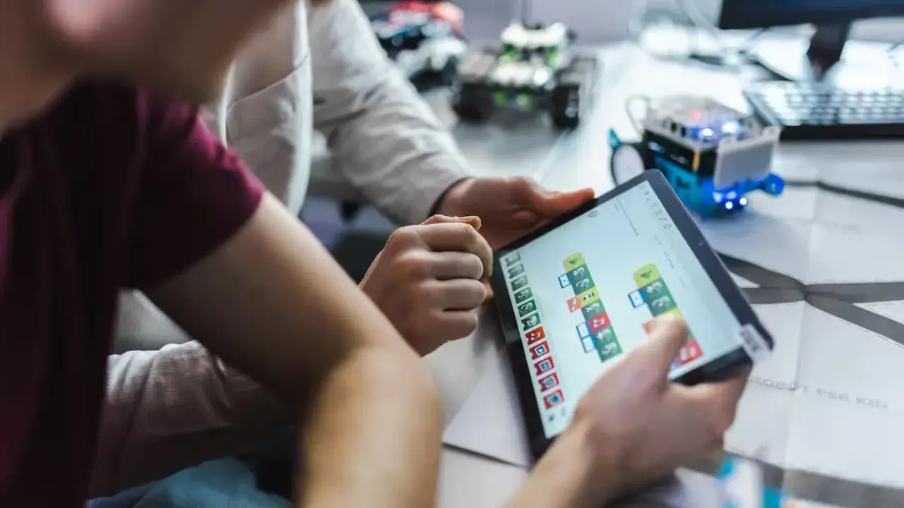 Dzieci programują robota na tablecie, ucząc się, czym zajmuje się informatyk.