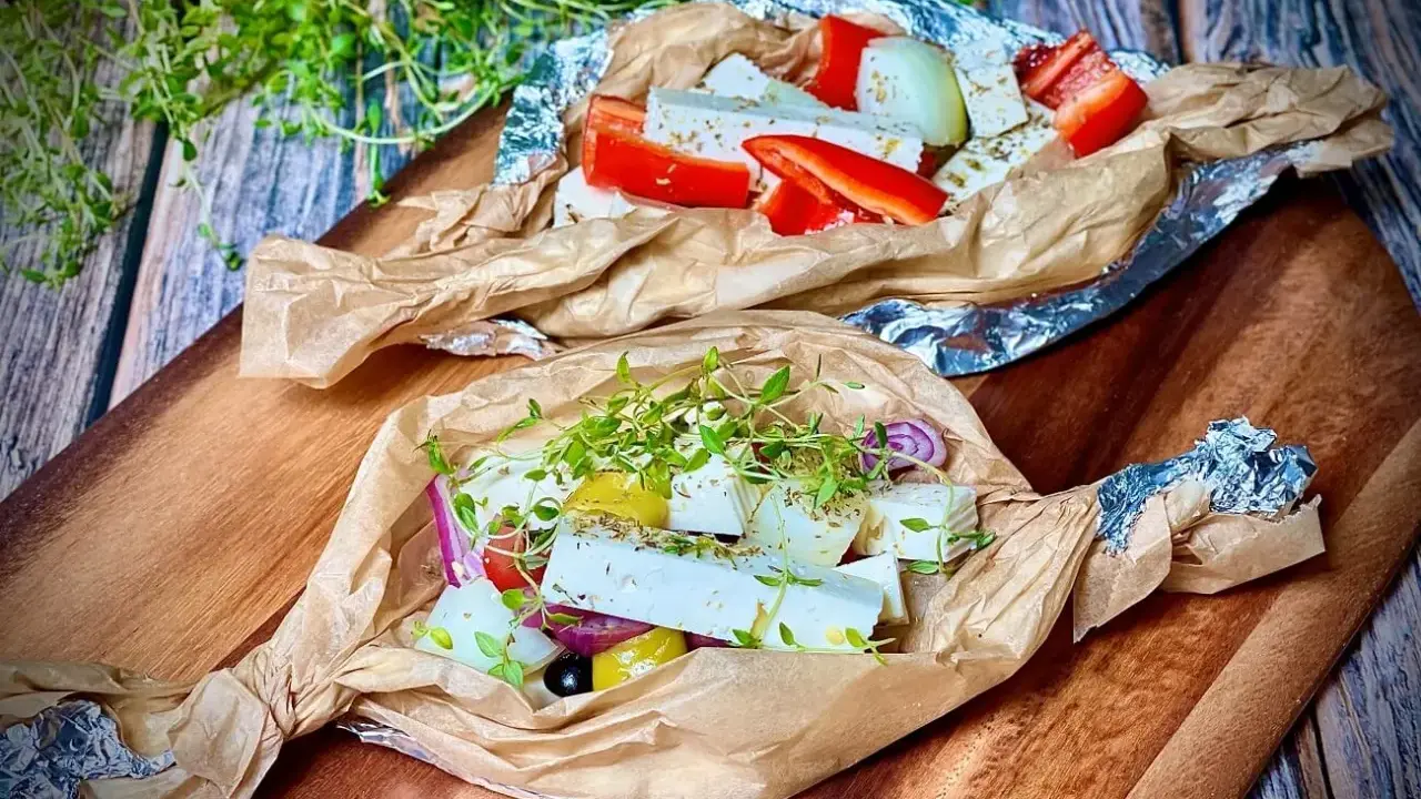 Zwei Päckchen mit Feta, Paprika, Zwiebeln und Kräutern warten darauf, gegrillt zu werden. Ein Genuss für den Gaumen!