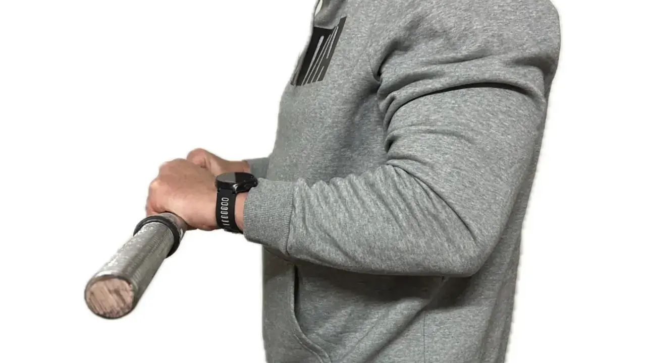 Person in grauem Hoodie macht einen Wrist Curl mit einer Hantel.