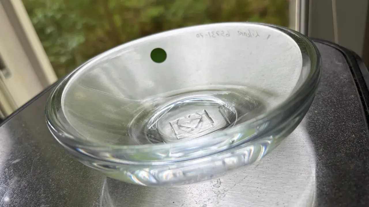 En Orrefors skål, ett tidlöst konstverk. Denna glasdesign med en grön prick och graverad text visar Orrefors skålar genom tiderna.
