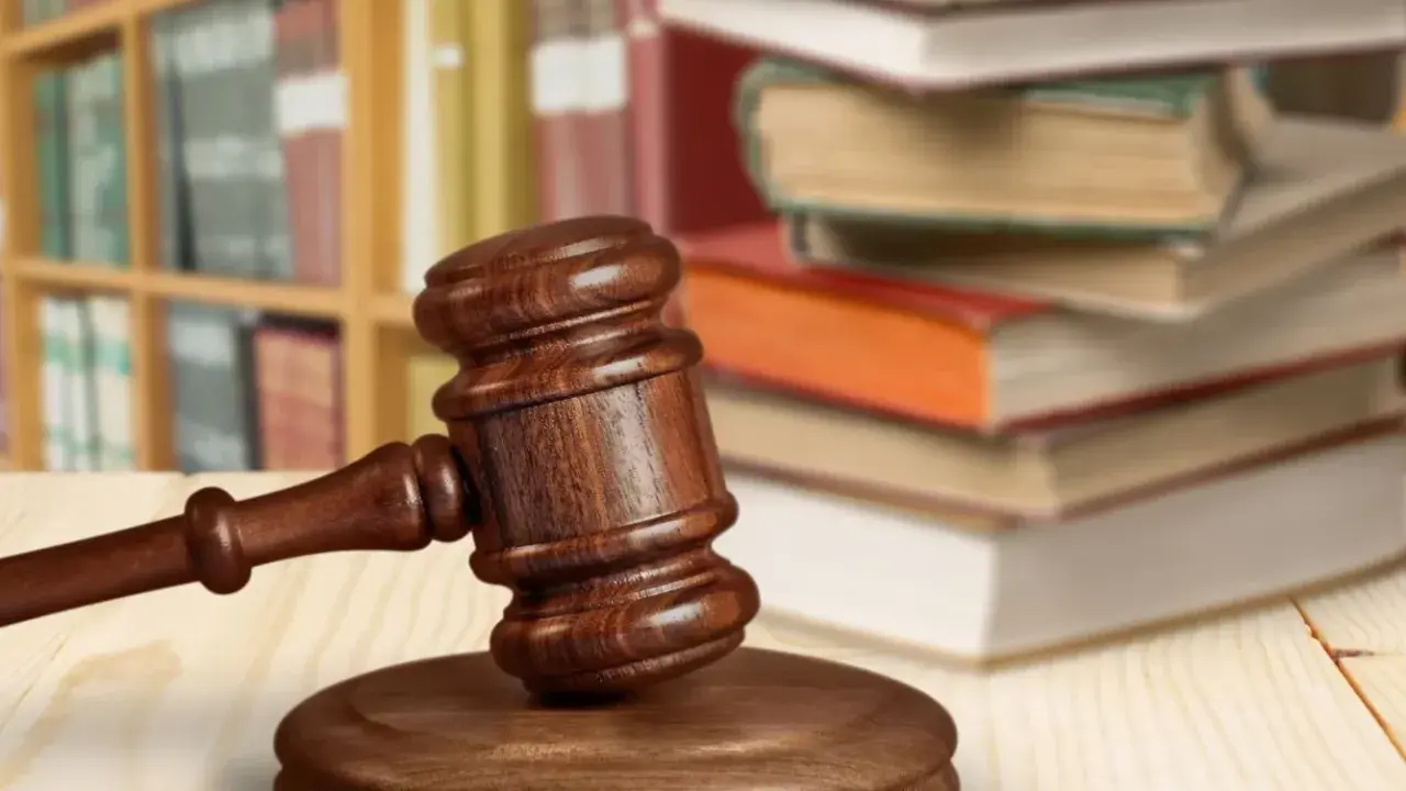 Martelletto da giudice su tavolo di legno, con libri e scaffali sullo sfondo. Simboleggia cosa succede dopo incidente probatorio.