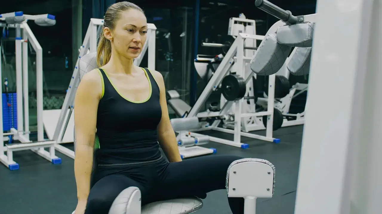 Frau trainiert ihre Adduktoren an einem Fitnessgerät im Studio.