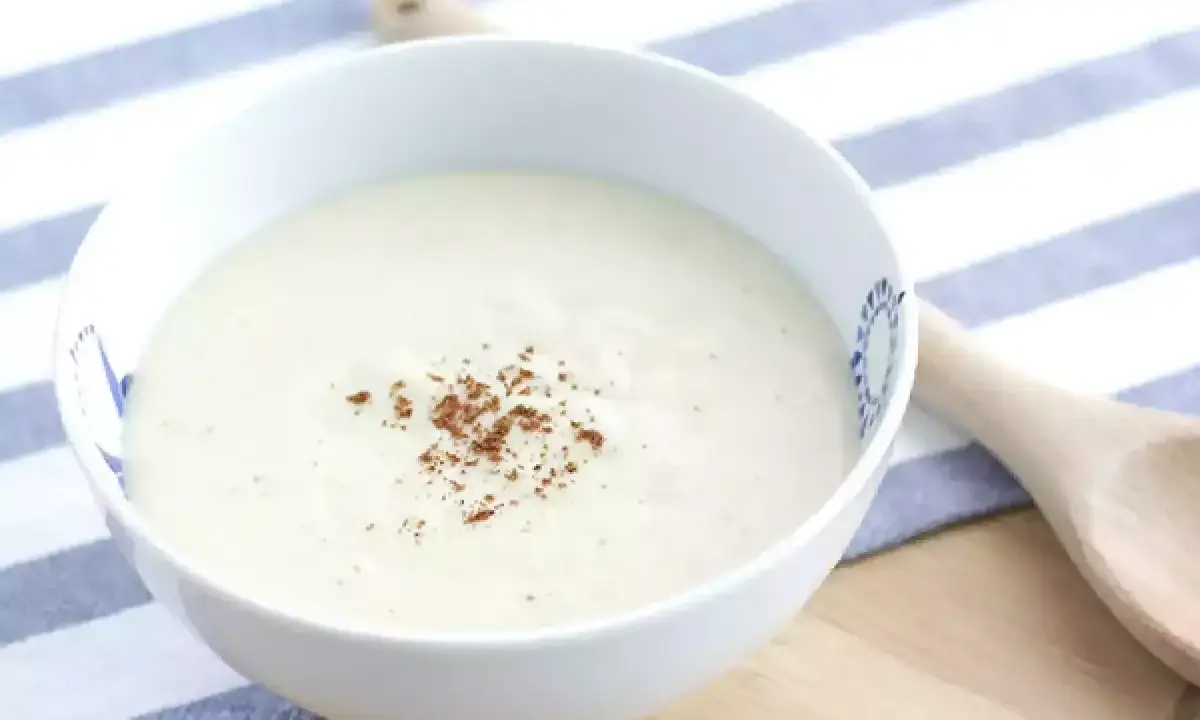 Un bol de sauce béchamel onctueuse, saupoudrée de noix de muscade râpée, prêt pour votre recette.