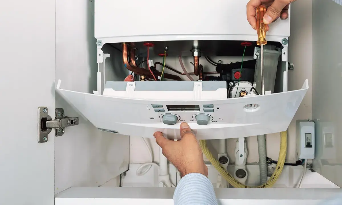 Hände reparieren einen Thermoflow Durchlauferhitzer. Eine Anleitung wird befolgt, um die Komponenten zu überprüfen.