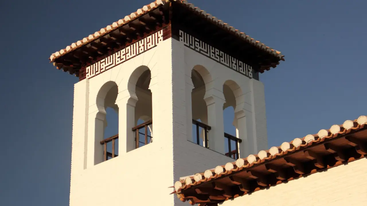Weiße Moschee in Granada mit arabischer Kalligrafie und maurischen Bögen.