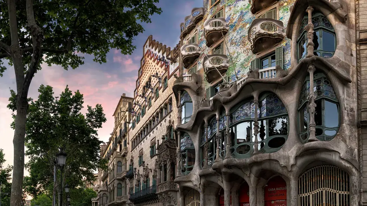 Casa Batlló in Barcelona, ein Meisterwerk des Art Nouveau, mit seinen organischen Formen und bunten Mosaiken, unter einem rosafarbenen Himmel.