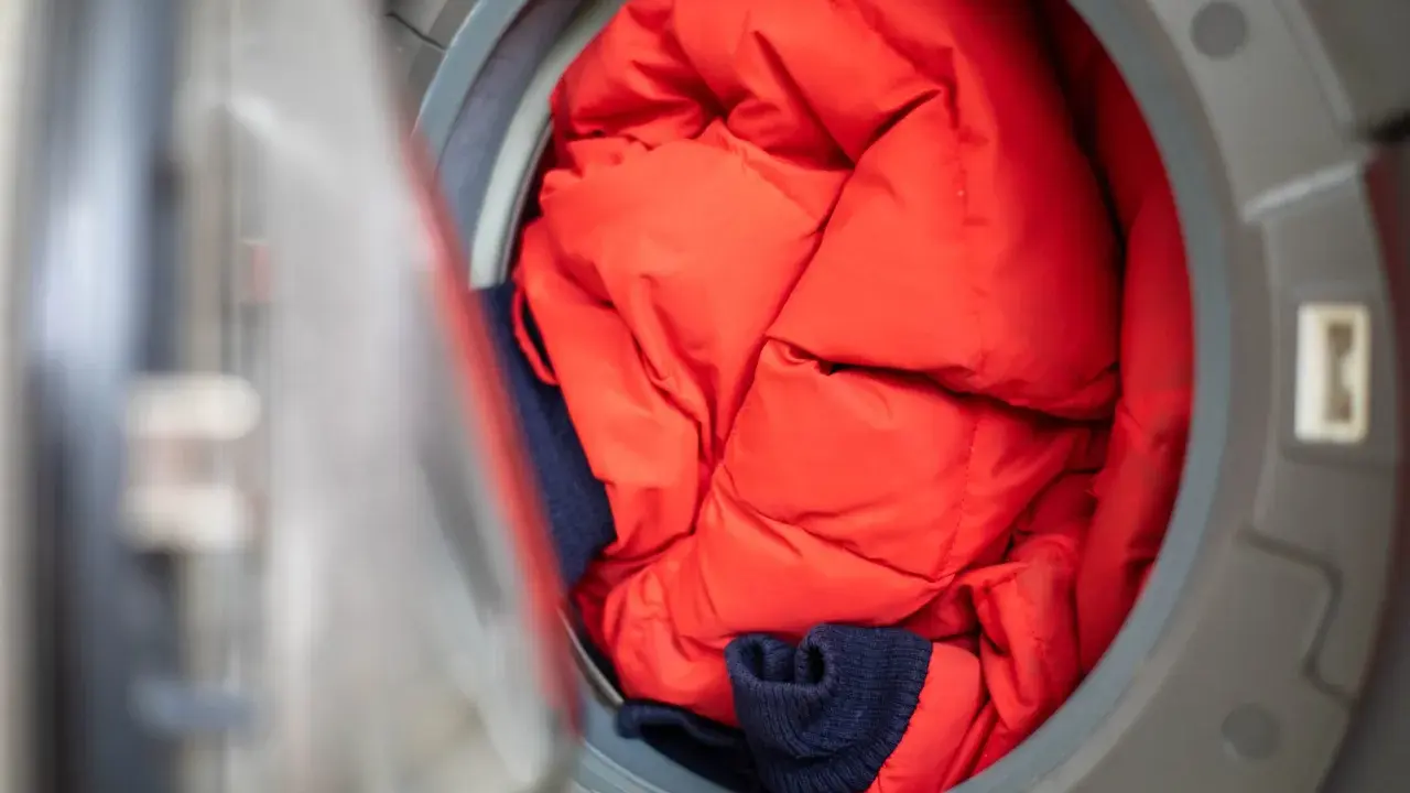 Czerwona kurtka puchowa i granatowy sweter czekają na program outdoor w pralce, by znów być gotowe na przygody.