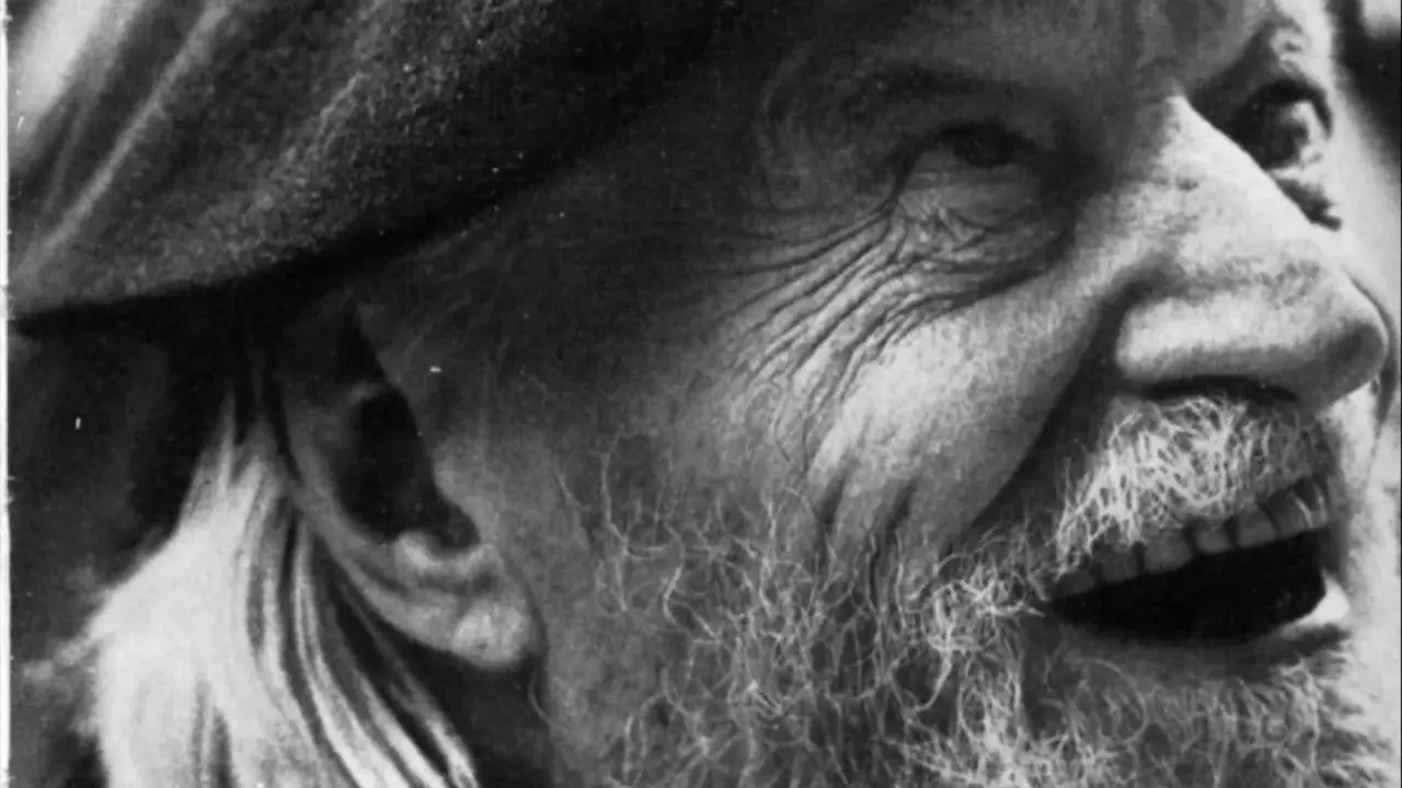 Primo piano di un uomo anziano con barba e cappello, il volto segnato dal tempo, come in un "giorno per giorno Ungaretti".