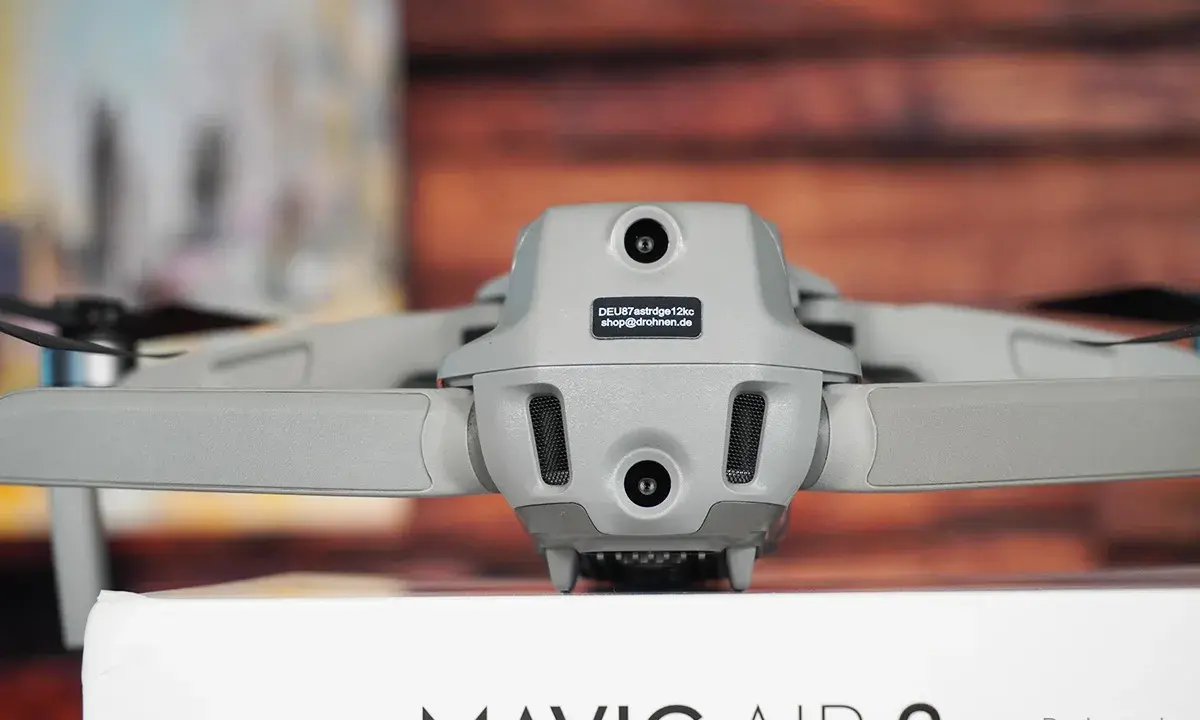 Graue Drohne Mavic Air 2 mit Kameras und Propellern. Auf dem Gehäuse ist ein Aufkleber mit der Kennung zur drohne registrieren.