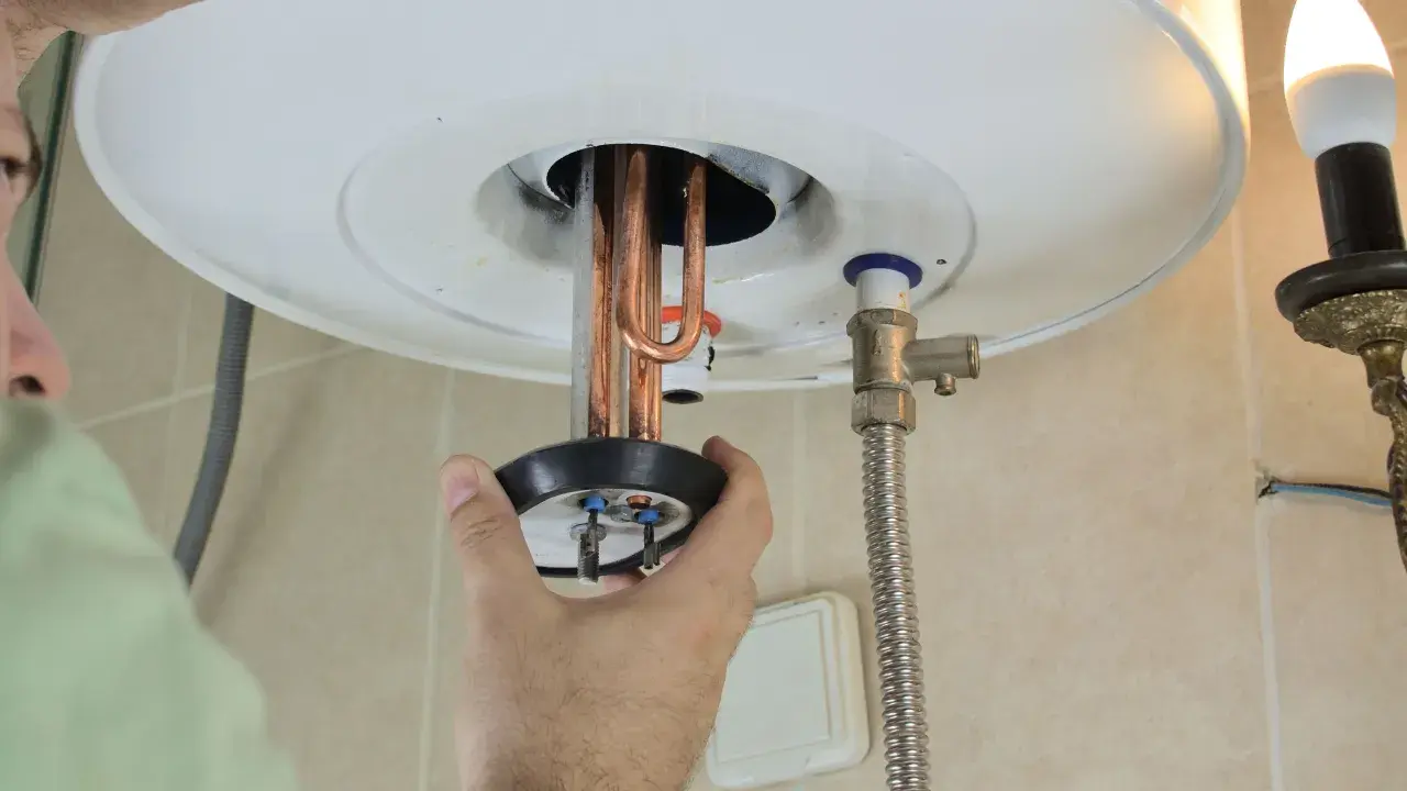 Mano ajustando la resistencia termoeléctrica de un calentador de agua.