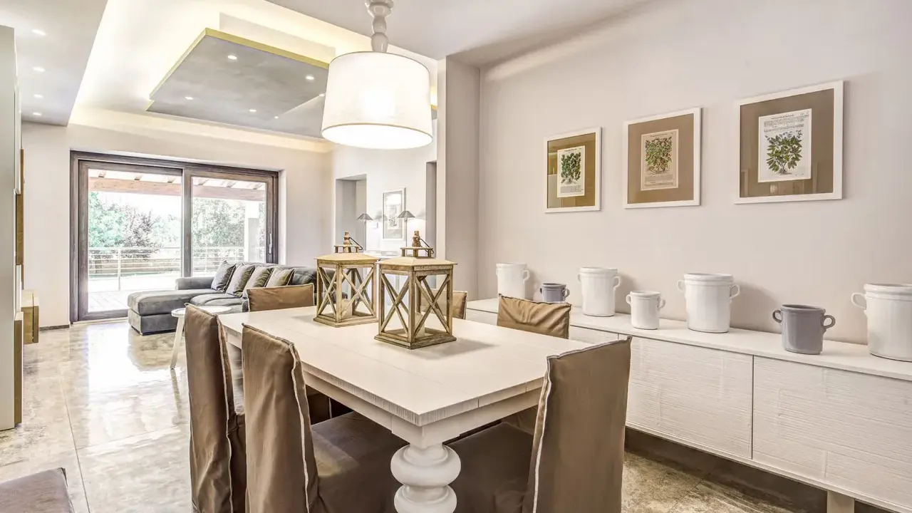 Un'elegante casa stile shabby chic moderno con tavolo da pranzo, divano e quadri botanici.