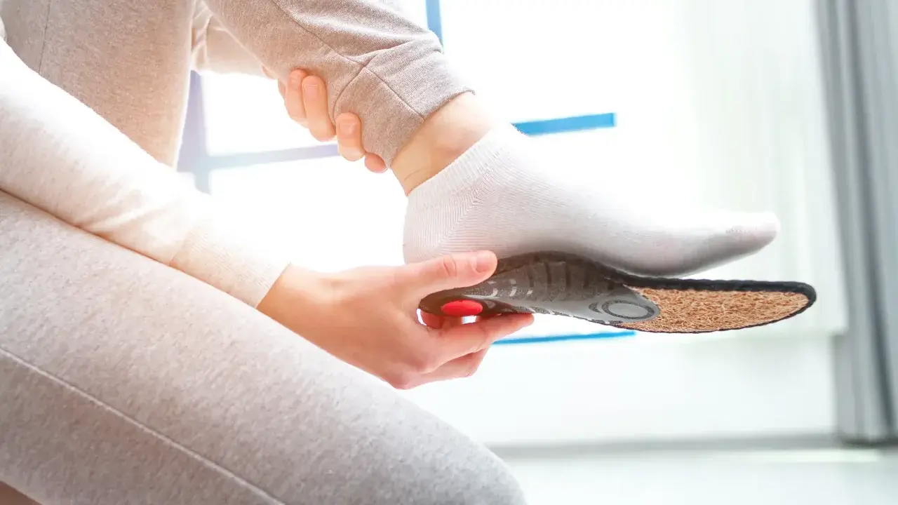 Une personne insère une semelle orthopédique dans sa chaussette. Une solution pour une pedicure remboursé.