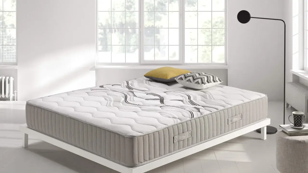 Colchón con diseño moderno sobre base blanca, ideal para quienes buscan confort y soporte. ¿Que es mejor para la espalda muelles o visco?