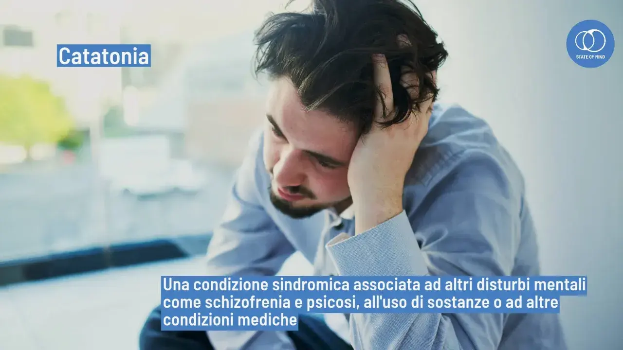 Uomo con mano tra i capelli, con testo "Catatonia" e la sua definizione. Il catatonia significato è una condizione sindromica.