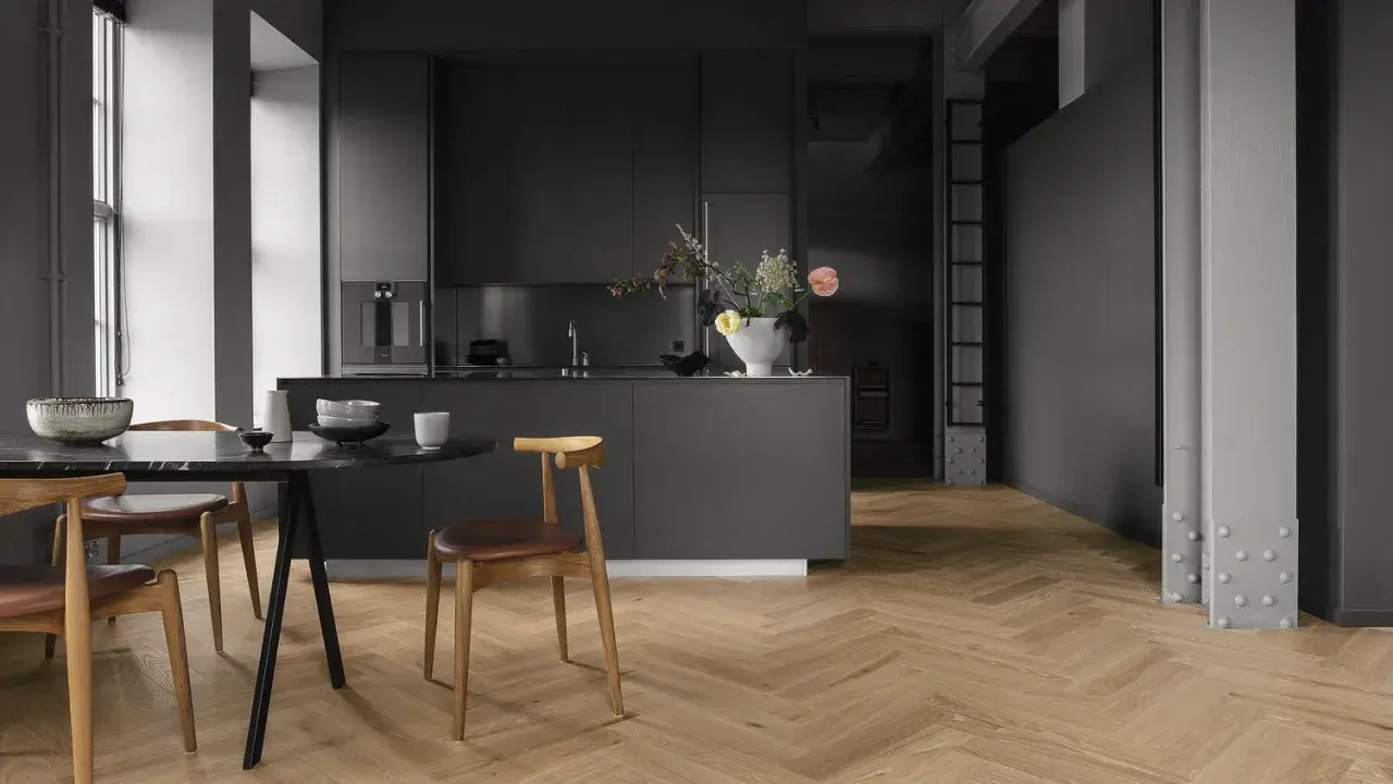 Cuisine moderne avec îlot central, chaises en bois et table en marbre. Le parquet en chevrons, bien que beau, est une mauvaise idée pour une cuisine.