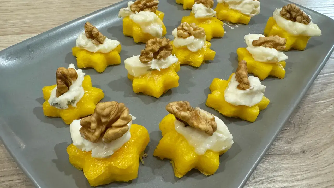 Stelline di polenta dorata con crema bianca e noci, perfetti antipasti di Natale per un tocco di sapore e colore.