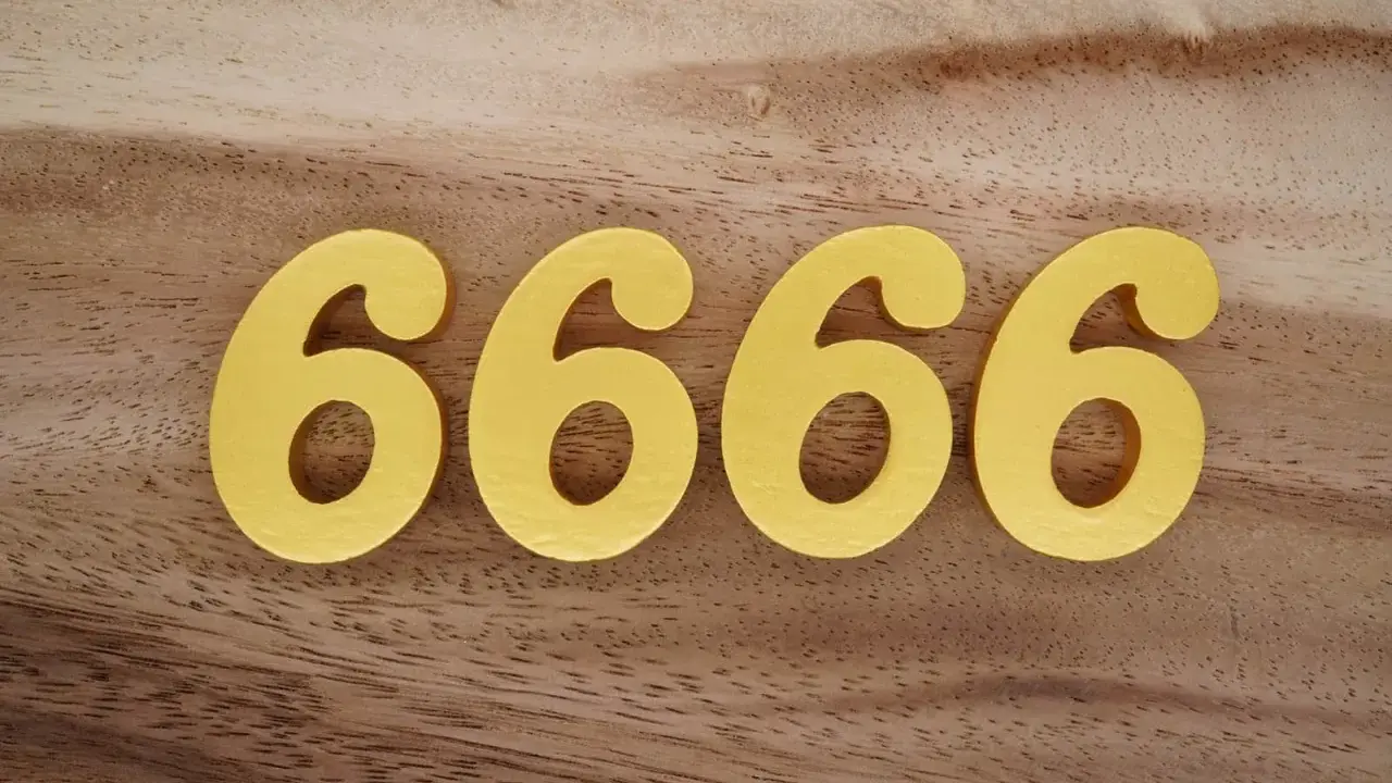 Quatre chiffres dorés 6666 sur fond de bois. Le 6666 signification est souvent lié à l'abondance et à la prospérité.