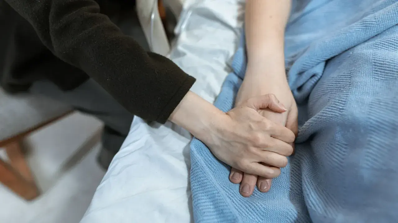 Mani che si stringono, un gesto di conforto per un paziente psichiatrico in un letto d'ospedale.