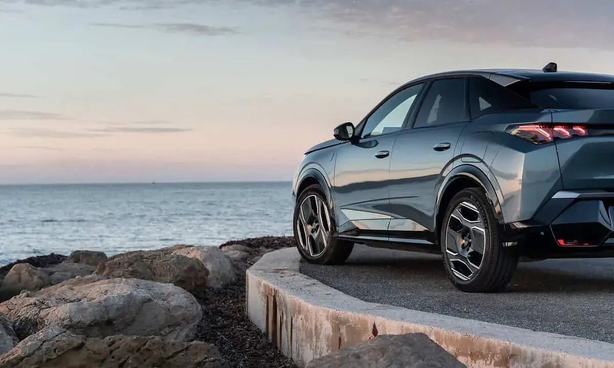 Nowy Peugeot 3008 hybryda na tle spokojnego morza i skalistego wybrzeża.