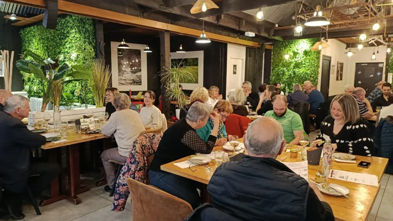 Un dîner convivial dans un restaurant à l'ambiance chaleureuse, où les convives savourent des mets qui incarnent la définition du "produit du terroir".