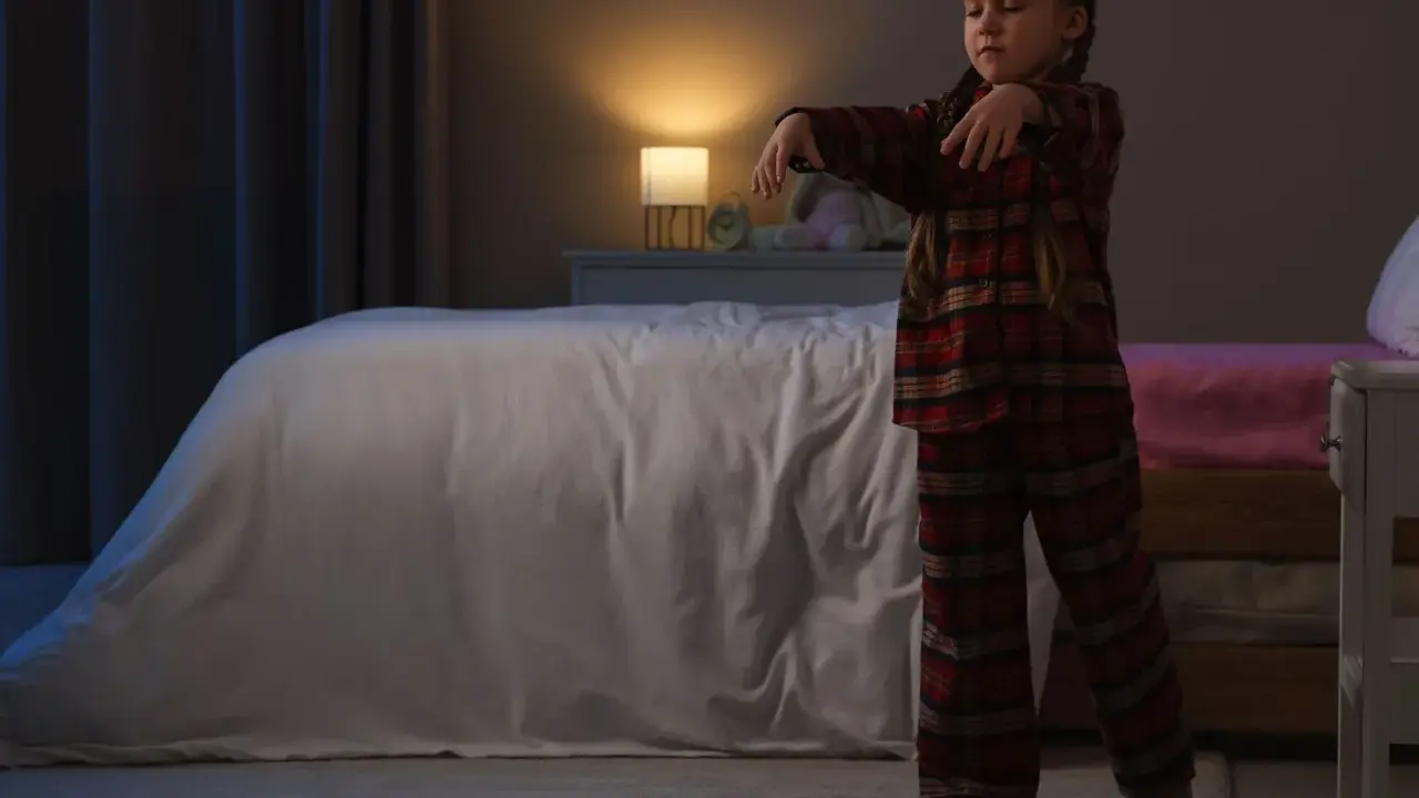 Bambina in pigiama a quadri cammina nel sonno, un esempio di sonnambulismo bambini.