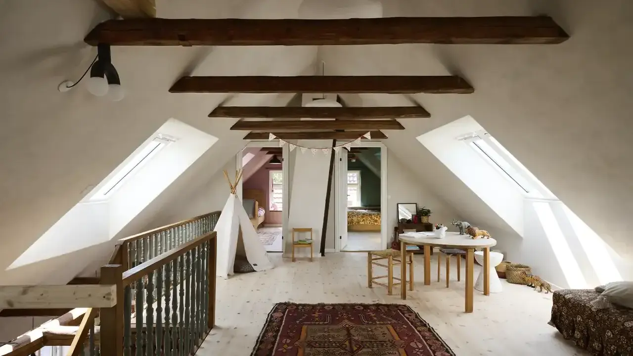 Idee per ristrutturare casa antica: mansarda luminosa con travi a vista, tappeto persiano, teepee e tavolino per bambini.