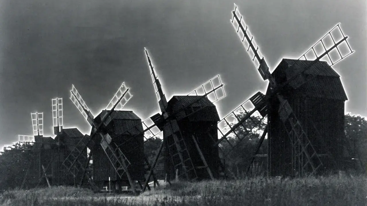 Mulini a vento in un campo, con un effetto di solarizzazione man ray che illumina le pale.