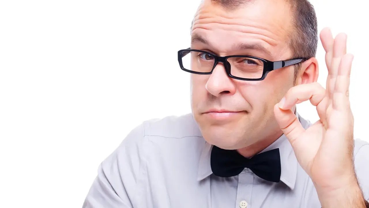 Mężczyzna w okularach i muszce pokazuje gest "OK". Okulary leżą idealnie na nosie, podkreślając jego pewność siebie.