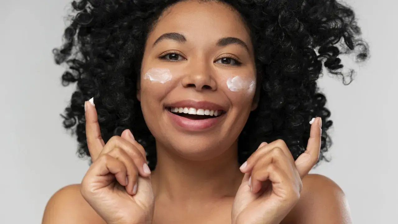 Donna sorridente con crema sul viso. La crema è non comedogeno, significa che non ostruisce i pori.