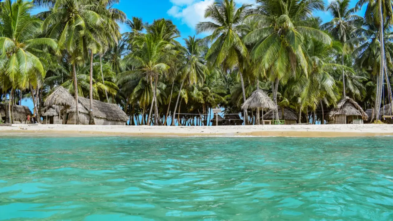 Rajska plaża San Blas z chatkami z liści palmowych i turkusową wodą.