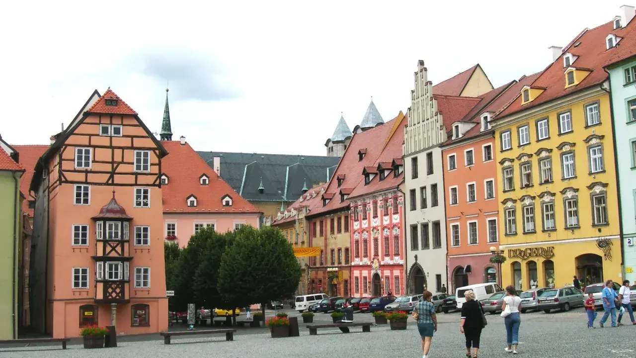 Kolorowe kamienice w **cheb** tworzą malowniczy rynek. Ludzie spacerują po brukowanym placu, podziwiając architekturę.