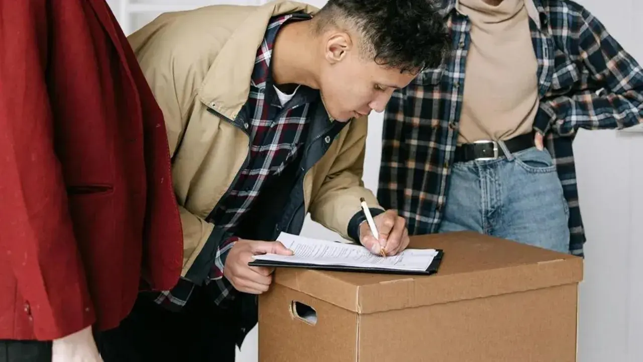 Jóvenes firmando un contrato de mudanza, quizás relacionado con la ley de arrendamientos urbanos.