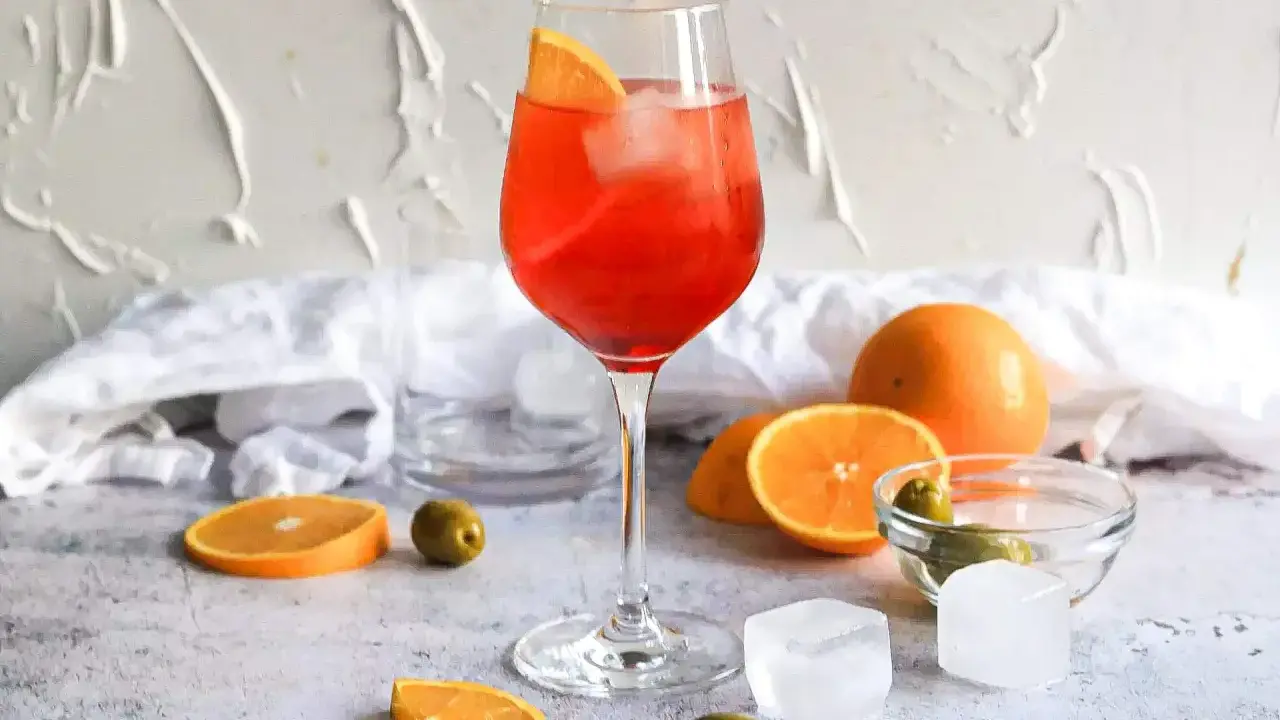 Ein Aperol Spritz mit Orangenscheibe und Eis. Orangen, Oliven und Eiswürfel deuten auf Aperol Spritz Varianten hin.