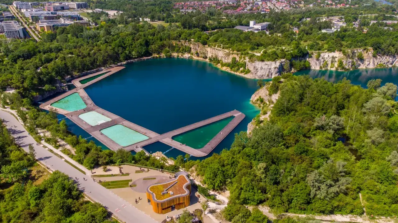 Widok z lotu ptaka na zalew Zakrzówek z drewnianymi pomostami i basenami. Trasa spacerowa wokół zbiornika.
