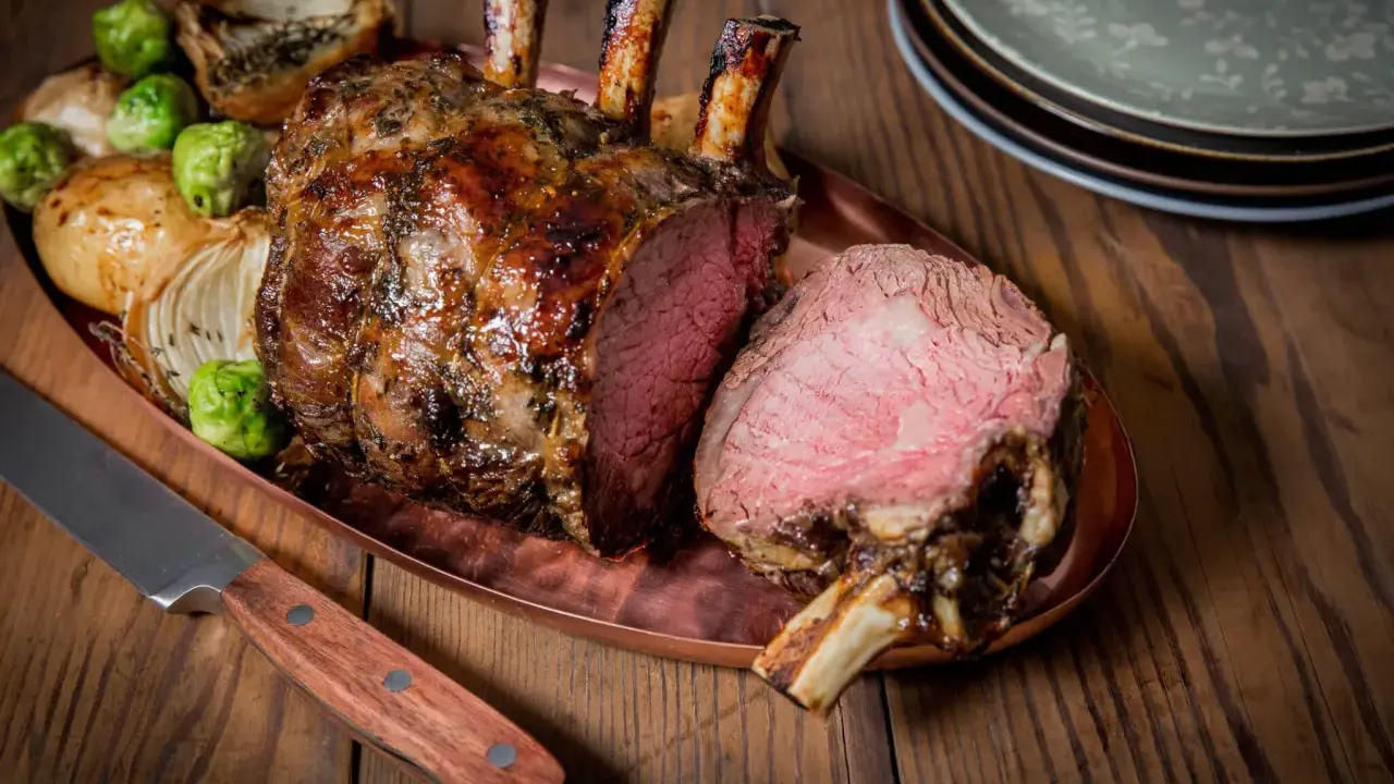 Carré d'agneau rôti 1 kg, saignant, servi avec des oignons et des choux de Bruxelles. Le temps de cuisson est parfait.