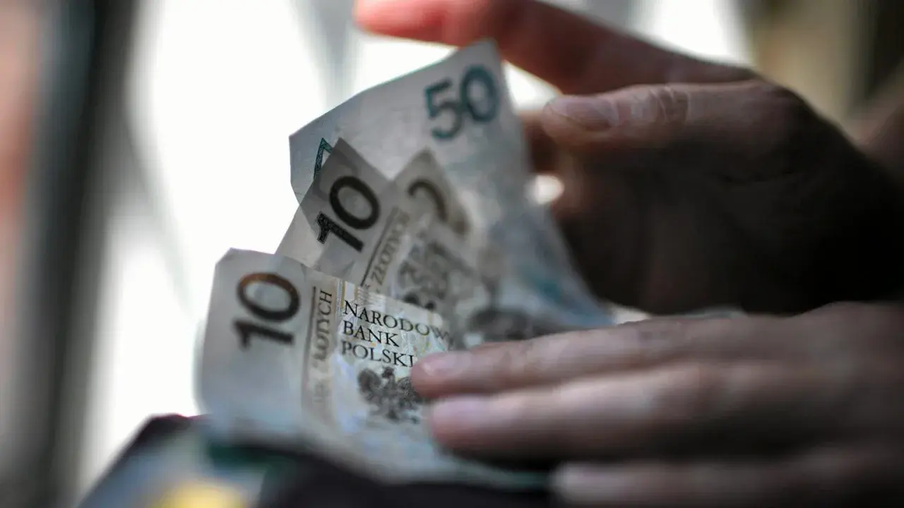 Dłoń trzyma polskie banknoty 10 i 50 zł. Zastanawiasz się, ile pieniędzy na bierzmowanie to odpowiednia kwota?