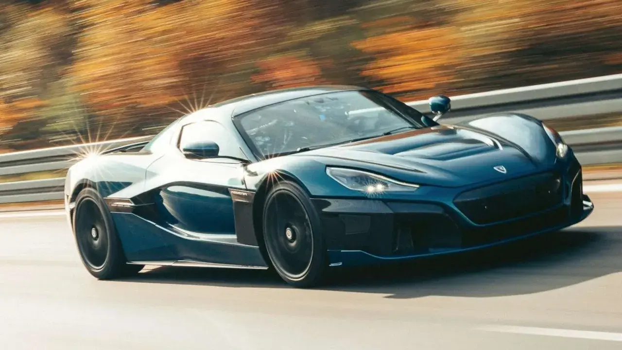 Blauer Rimac Nevera rast auf einer Straße, die Bäume im Hintergrund verschwimmen. Ein Beweis für die unglaubliche rimac nevera top speed.