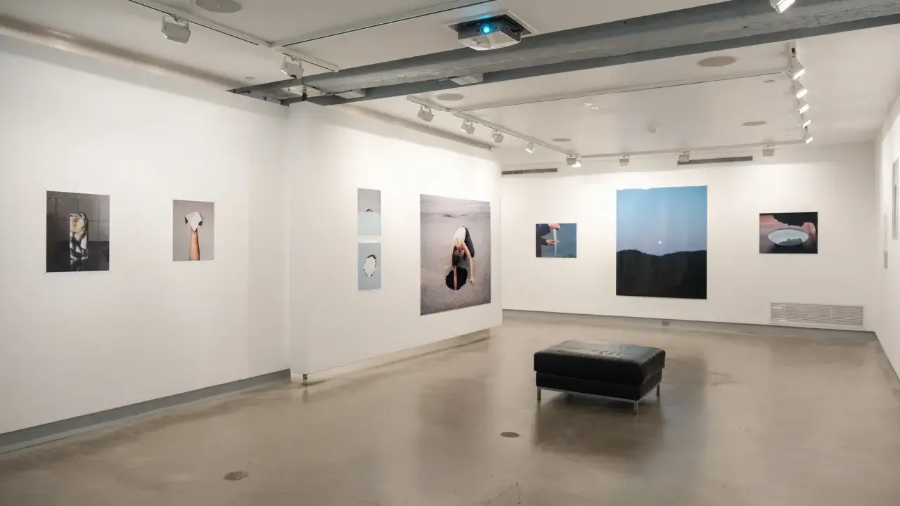 Art exhibition at blue sky gallery Portland, featuring abstract photography and a black leather ottoman.