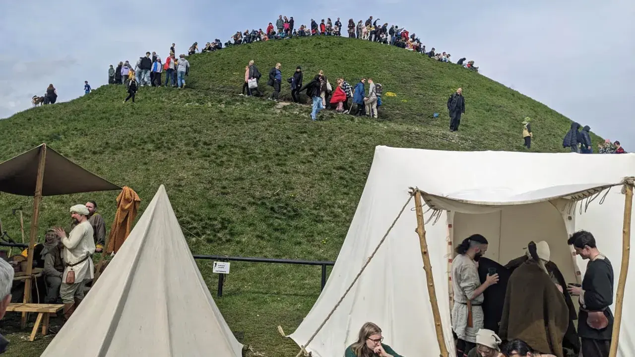Ludzie wchodzą na Kopiec Kraka, a u jego podnóża rozstawiono historyczne namioty.