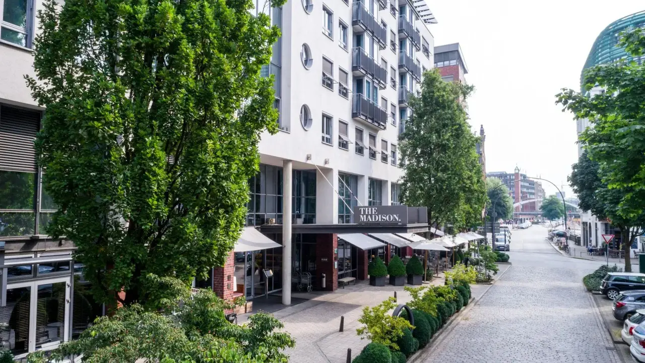 Das Madison Hotel Hamburg mit Außenbereich und Blick auf eine kopfsteingepflasterte Straße.