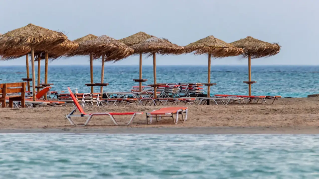 Plaża Elafonisi z rzędem słomianych parasoli i leżaków, gotowa na gości.