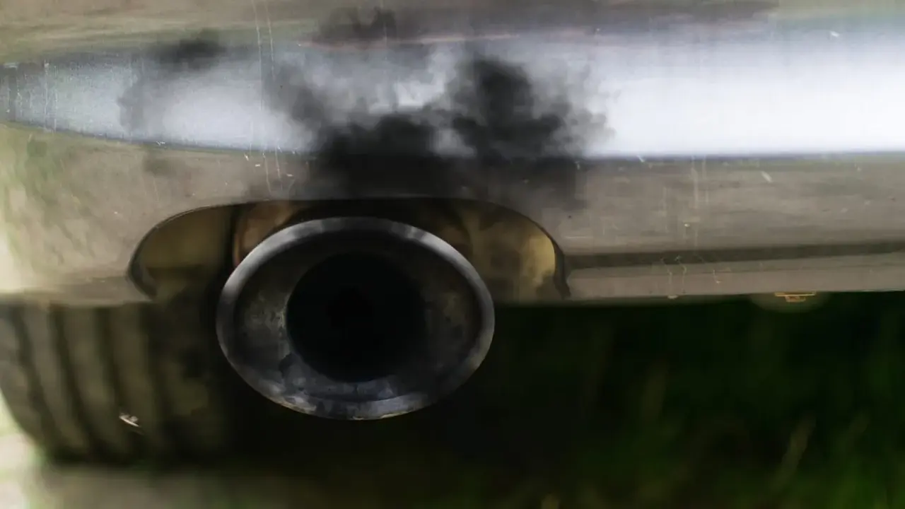 Zanieczyszczony układ wydechowy samochodu, czarny dym wydobywa się z rury. Czas na czyszczenie DPF.
