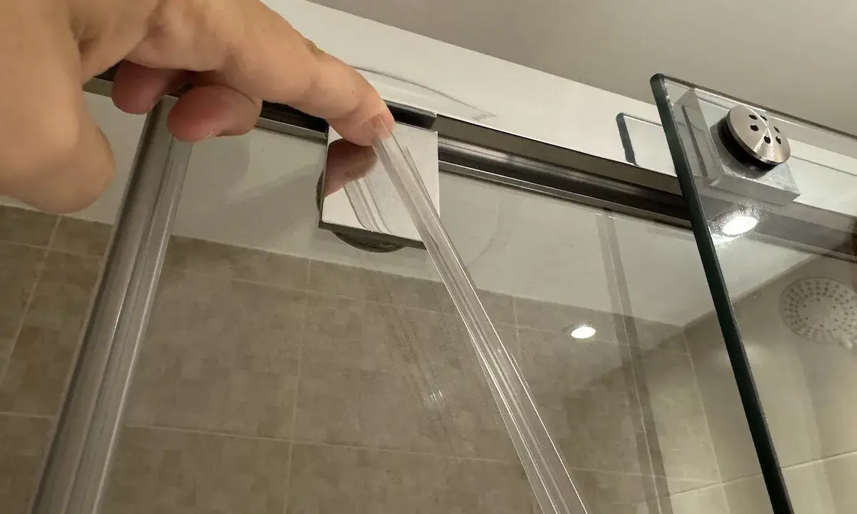 Mano insertando una goma nueva para cambiar gomas mampara ducha.