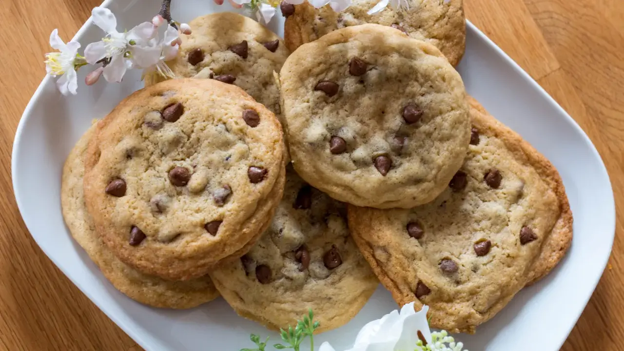 Schokoladenkekse, die an das Subway Cookies Rezept erinnern, auf einem Teller mit Kirschblüten.