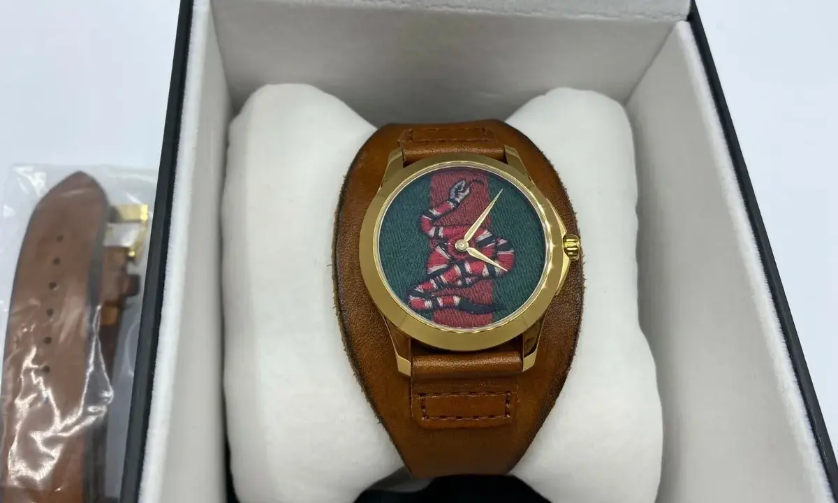 Orologio Gucci serpente con quadrante verde e cinturino in pelle marrone, presentato nella sua scatola.