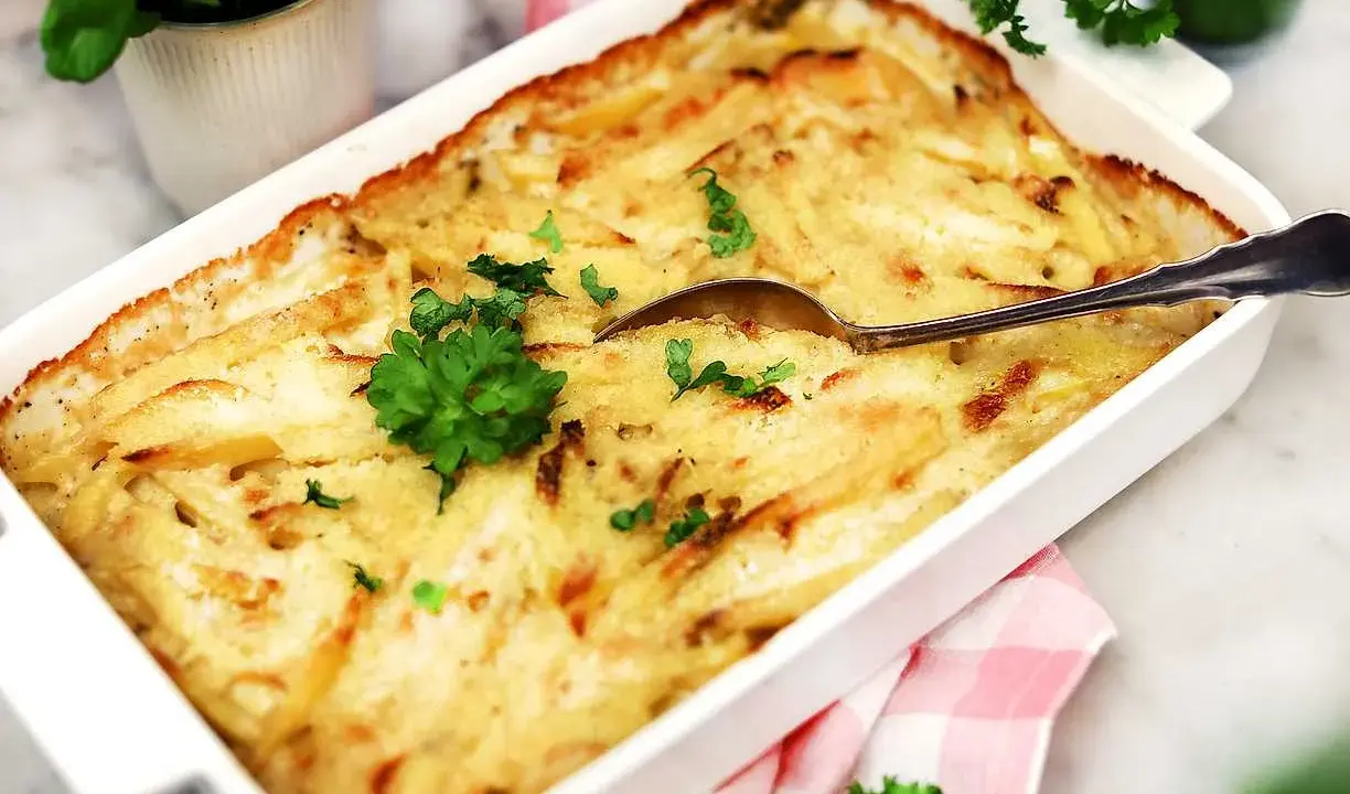 En krämig Janssons frestelse i en vit form, redo att serveras. Perfekt för ett julbord eller en mysig middag.