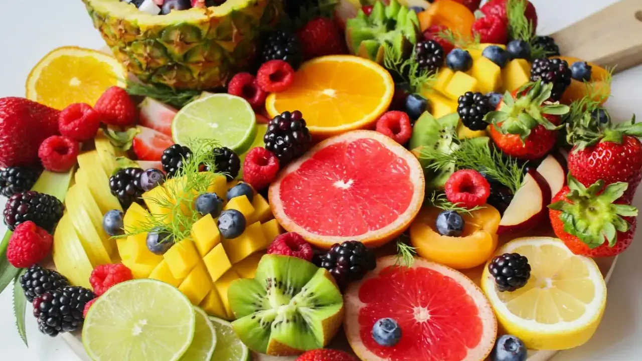 Kolorowa taca pełna owoców: ananas, maliny, borówki, truskawki, mango, kiwi, pomarańcze, grejpfruty, limonki, cytryny. Idealna na dietę owocową.